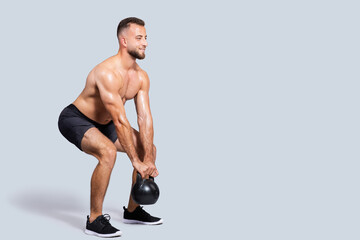 Happy sweat strong muscular millennial caucasian man with beard, naked torso make exercises with kettlebell
