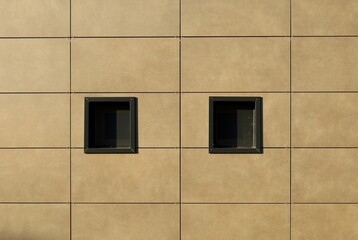 Small insulated windows on brown stone tiled ventilated facade. Background and texure.