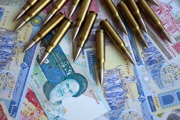 Many bullets and iranian rials money bills close up. Concept of terrorism funding or financial...