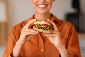 Close-up of woman's smile as she holds delicious burger