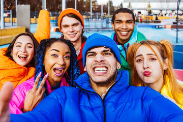 Multiracial group of young friends meeting outdoors in winter - Multiethnic students with colorful winter jackets and stylish outfits having fun in the city