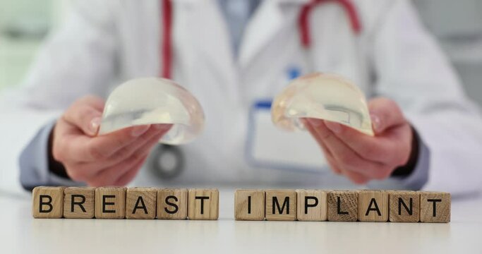 Plastic surgeon holding silicone implants and text in hands