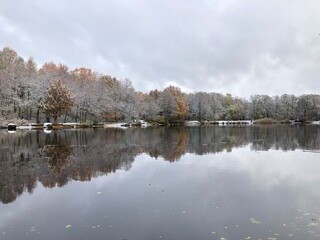 Fototapeta premium trees covered with snow and frost, as if silver, are reflected in the smooth mirror water of the river, winter landscape