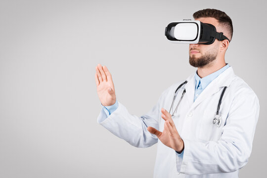 Doctor man using virtual reality headset, interacting on grey background, free space