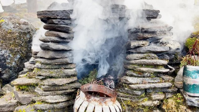 Holy puja ceremony fireplace. Smoke flying up and covering Holy buddhist praying multicolored flags with mantras slow motion video in Tuli Kharka village at 4200m on Mera peak climbing route.