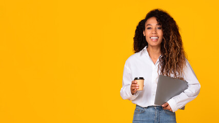 black young lady holding laptop and coffee cup, yellow background