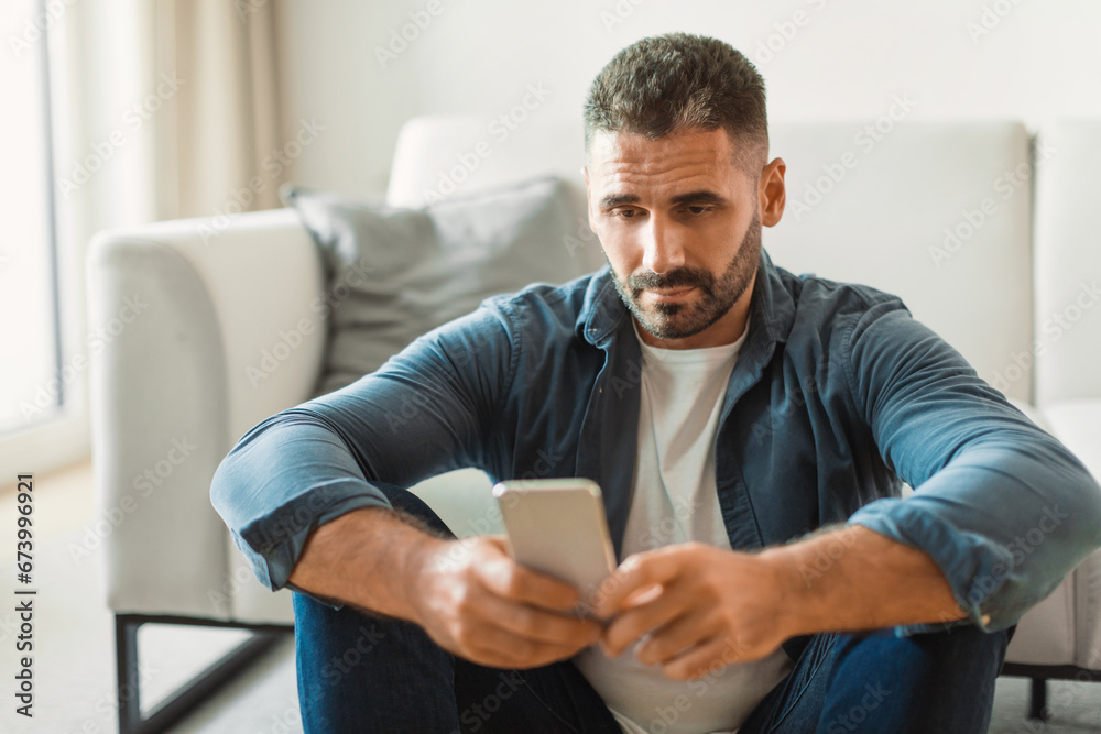 Poster middle aged guy texting on smartphone while having issues indoor