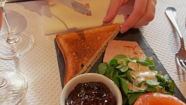 Close up video of woman spreading Foie Gras on toast in restaurant in Paris.