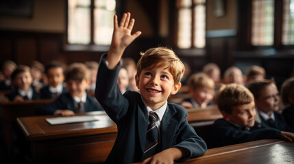 student at a desk in a school class raises his hand, child, smart kid, children, study, learning, classroom, knowledge, lesson, pupil, schoolboy, boy, uniform, european, tie, smile, portrait, face - obrazy, fototapety, plakaty
