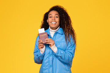 Happy black lady with passport and tickets on yellow background