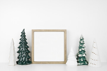 Christmas mock up with wooden frame and tree decor. Square frame on a white shelf against a white...