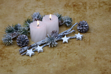 Weihnachts und Adventsdekoration: Zwei weiße brennende Kerzen mit Sternen, Tannenzapfen, Zweigen...