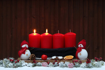 Zweiter Advent: Adventsdekoration mit roten Kerzen, Weihnachtsschmuck und Dekofiguren im Schnee.