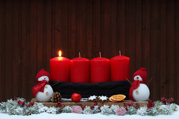 Erster Advent: Adventsdekoration mit roten Kerzen, Weihnachtsschmuck und Dekofiguren im Schnee.	