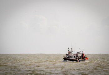 A local fishing boat returning from a day at sea, Image shows a navy blue fishing boat returning to shore on a windy day, October 2023