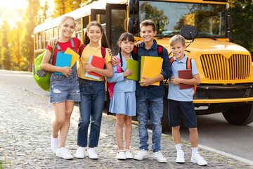 Diverse group of kids standing outside by yellow school bus,