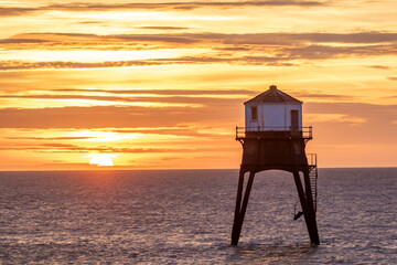 sunrise over a old lighthouse in the sea, Dovercourt low lighthouse, built in 1863 and discontinued in 1917 and restored in 1980 the 8 meter lighthouse is still a iconic sight, October 2023