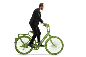 Naklejka premium Profile shot of a businessman riding a green eco friendly bicycle out of the saddle