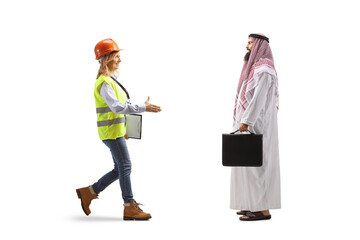 Full length profile shot of a female engineer walking and meeting a saudi arab businessman