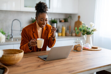 Successful African businesswoman looking at laptop screen celebrating new business opportunity pumping fist while expressing joy. - obrazy, fototapety, plakaty