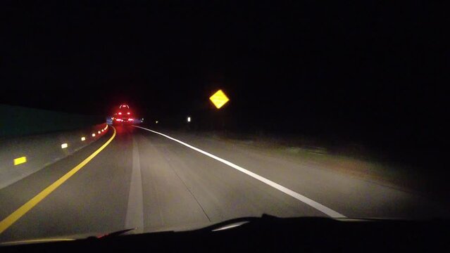 Following Large Transport Truck Trailer With Red Lights On Highway Interstate At Night With Construction Barriers