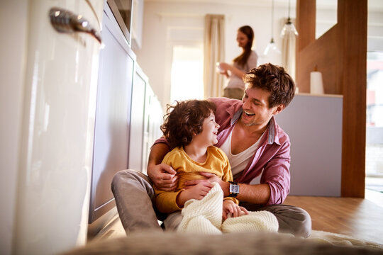 Happy father hugging son with mother in background at home