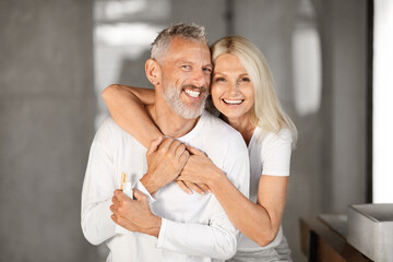 Portrait Of Happy Senior Spouses Embracing In Bathroom Interior