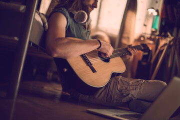 Bearded man playing guitar at home - obrazy, fototapety, plakaty