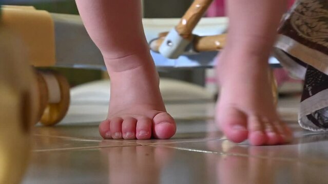 close up of a baby's feet moving on tiptoe using a baby walker that has lots of wheels.