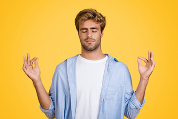 European man meditating, om hand gesture, on yellow background