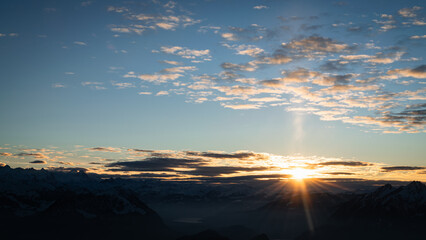 Sunset with cloudy sky behind mountains of Swiss alps - winter landscape