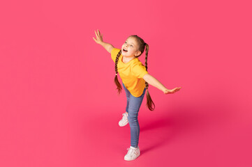 Cheerful Preteen Caucasian Girl Fooling Over Pink Background, Pretending Flying © Prostock-studio
