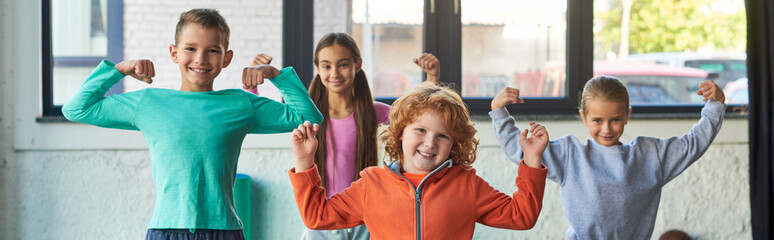 four cute little children in sportswear playing muscles and smiling at camera, child sport, banner