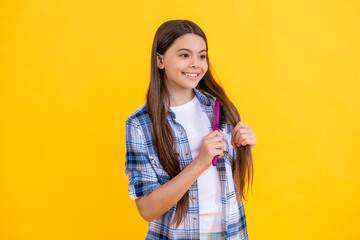 cute teen girl with hairbrush. teen girl using a hairbrush to style her hair isolated on yellow. teen girl holding hairbrush while brushing her hair. teen girl brushing long hair with hairbrush