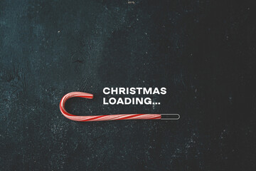 Christmas loading inscription on a black background and candy - obrazy, fototapety, plakaty