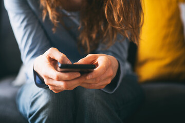 Young woman using a mobile phone on the couch at home