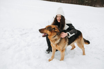 Young woman walk the dog German Shepherd in winter field forest, running playing with snow, training the animal in harsh conditions, wind blowing. Christmas Time, New Year