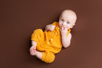 a small child lies on a brown background. newborn boy. baby's first photo shoot