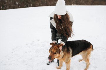 Young woman walk the dog German Shepherd in winter field forest, running playing with snow, training the animal in harsh conditions, wind blowing. Christmas Time, New Year