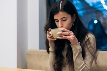 Pretty young woman sitting in cafe, drink cup of coffee hot beverage. Chill, relax, lunch 