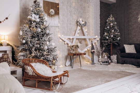 Cozy flat apartment photo studio room sled sleigh green Christmas Tree gifts presents garlands, candles decorated toys balls interior New Year lights glowing bokeh 

