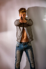 A man with no shirt holding a gun. Photo of a shirtless man with an open jacket on nude torso, holding a firearm