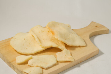 Three shrimp crackers on a wooden cutting board isolated on a white background