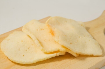 Three shrimp crackers on a wooden cutting board isolated on a white background