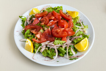 Green salad with arugula, lamb and tomatoes. Healthy vegan dish. Top view at table. Turkish Coban (choban) salata or Shepherds salad, Akdeniz salad in white bowl.