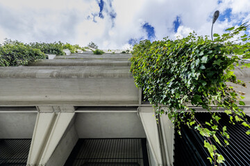 Facades of residential buildings built of concrete with hanging gardens on the balconies and a sky...