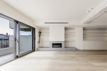 Fototapeta premium Front image of the living room of a recently renovated modern home with built-in furniture on one side, gray fireplace, wooden floors and terrace with views of the neighbors