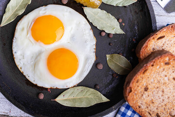 Fried eggs in a frying pan with pickled cucumbers.