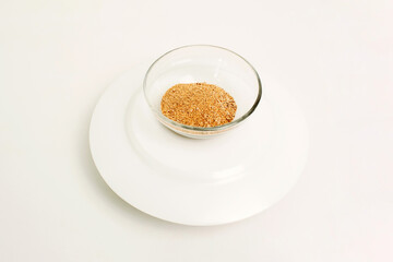 Dry ground ginger in a glass plate on a white background. Close-up.