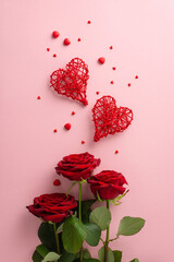 Love-filled St. Valentine's Day scene. Top-view vertical image featuring rattan heart ornaments, red rose bouquet, sugar sprinkles against soft pink background, perfect for advert